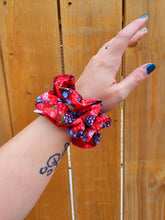 Load image into Gallery viewer, A person's forearm showcasing two matching red and blue berry patterned scrunchie hair accessory.