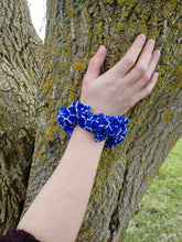 Load image into Gallery viewer, blue scrunchie with white lattice pattern on a wrist