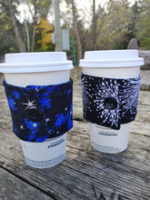 Load image into Gallery viewer, blue and black starry night prink drink cozie on a cup beside dandelion print drink cozie on a cup