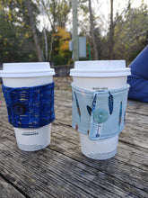 Load image into Gallery viewer, teal drink cozie on a cup beside a blue drink cozie on a cup