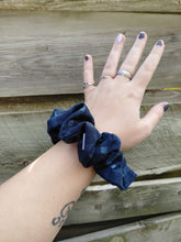 Load image into Gallery viewer, A person's forearm showcasing a blue checkered scrunchie hair accessory.