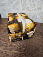 Load image into Gallery viewer, end view of cosmetic bag with gold open book print lack back ground white zipper on top 
