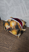 Load image into Gallery viewer,  top view of cosmetic bag with gold open book print lack back ground white zipper on top  red plain lining 
