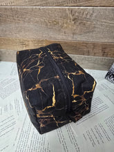 Load image into Gallery viewer, Black and gold marbled pouch on a book
